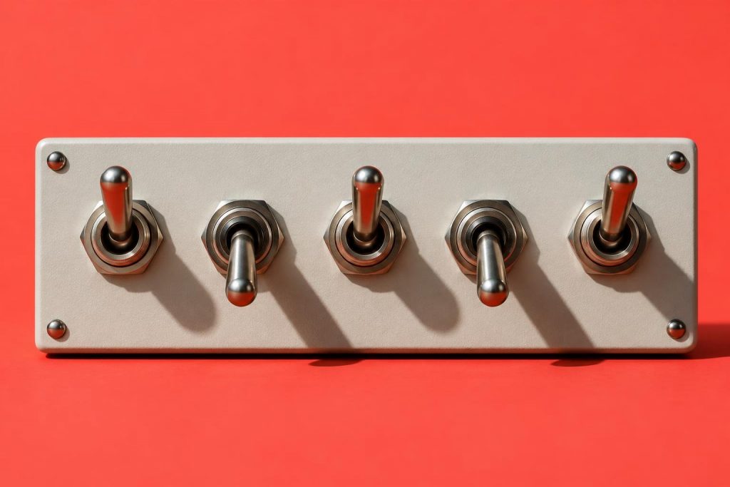 Panel con cinco interruptores metálicos de palanca, unos arriba y otros abajo, sobre un fondo rojo coral